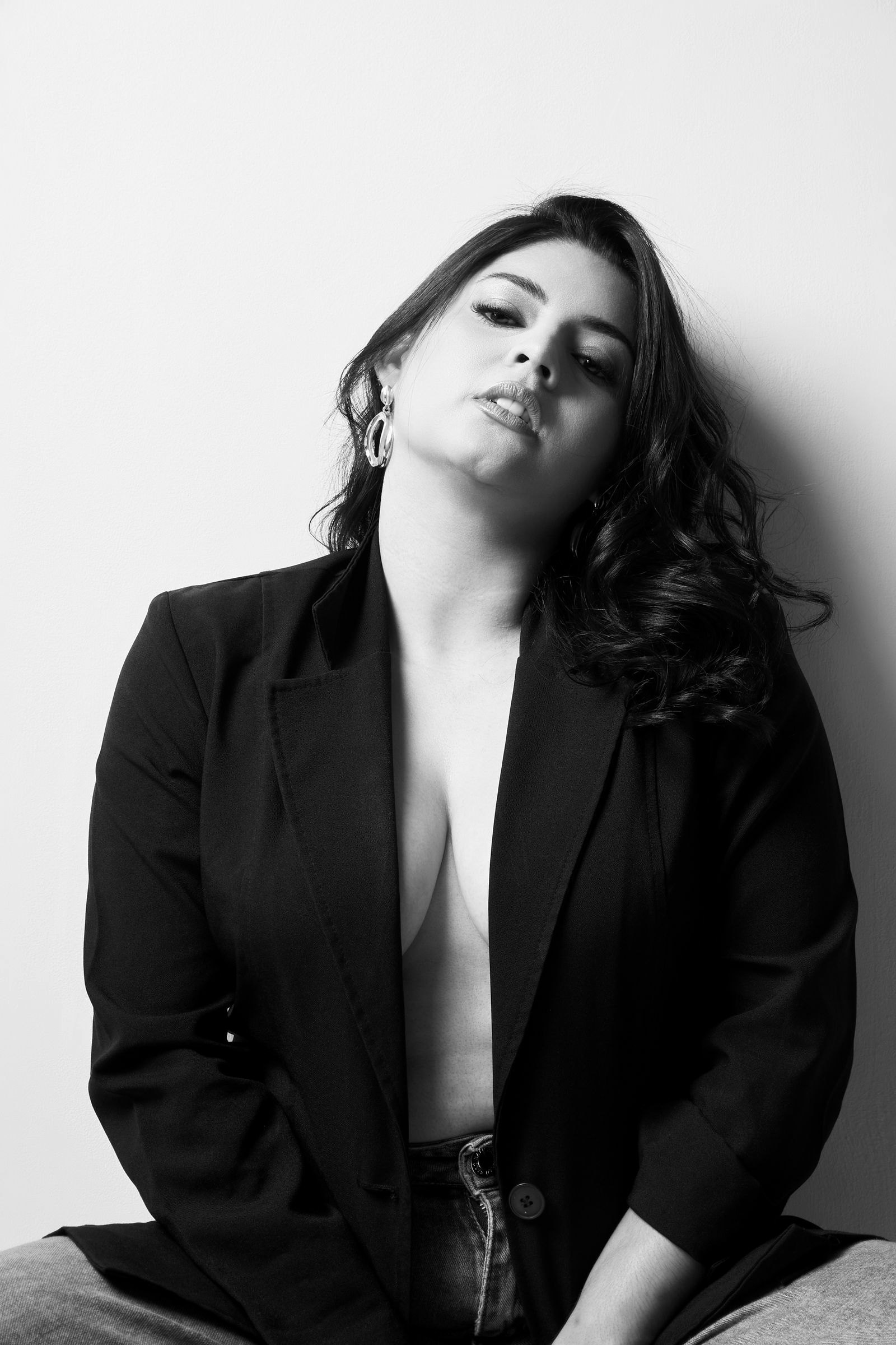 A woman in a tailored blazer posing in a studio portrait