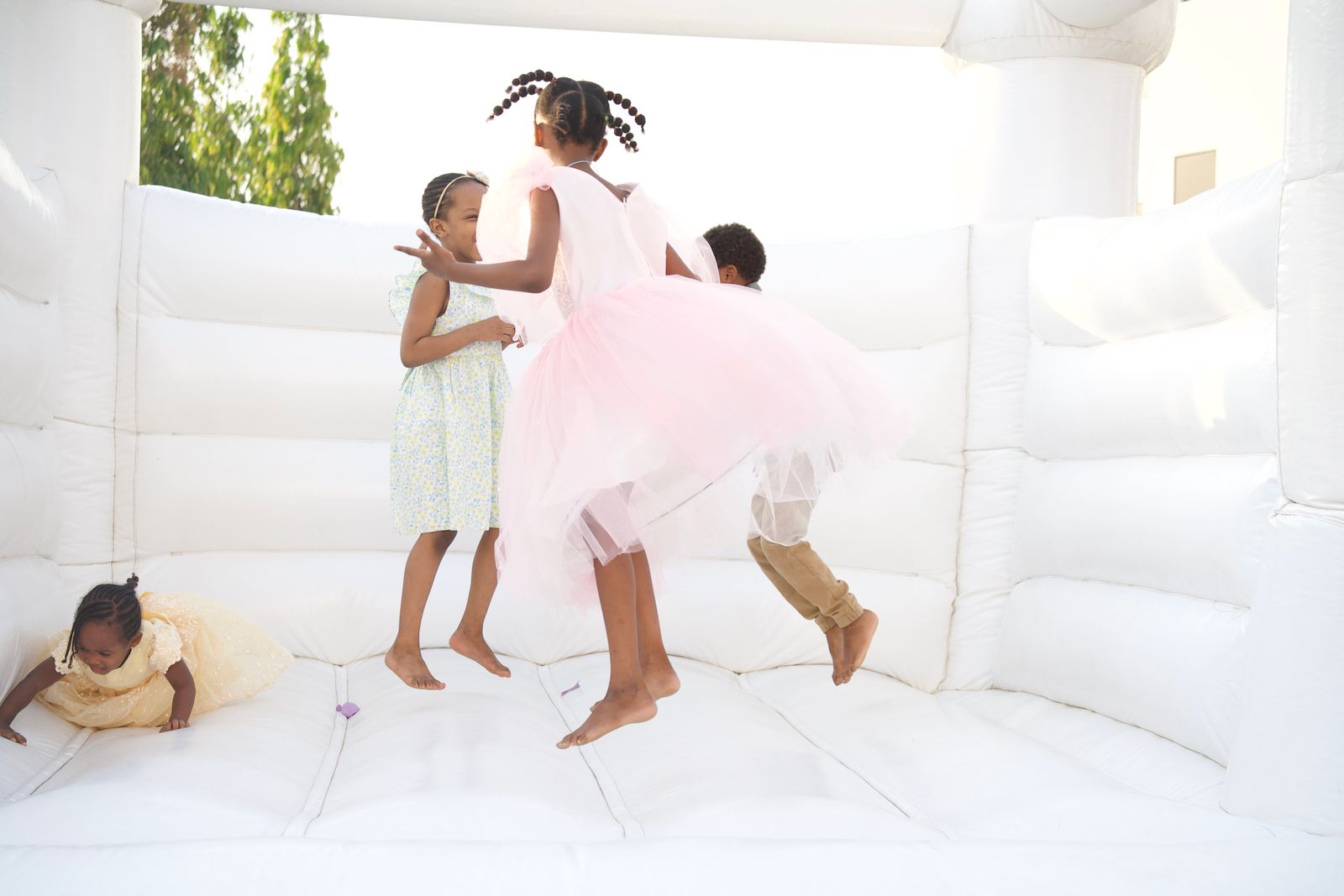 Children in party dresses playing in a white bounce house