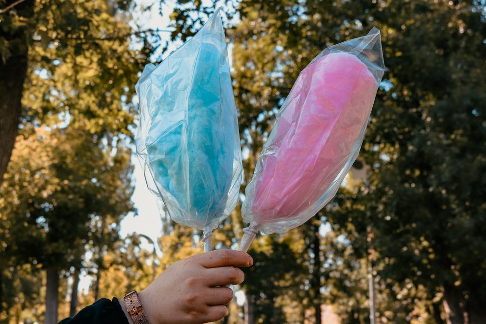 Pink and blue cotton candy held up outdoors
