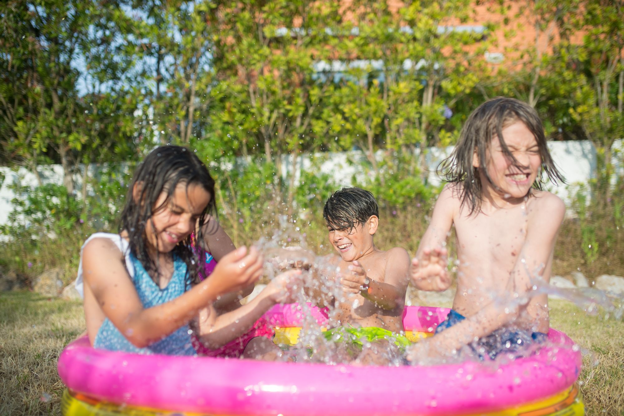 Kids splashing in an inflatable pool in a backyard