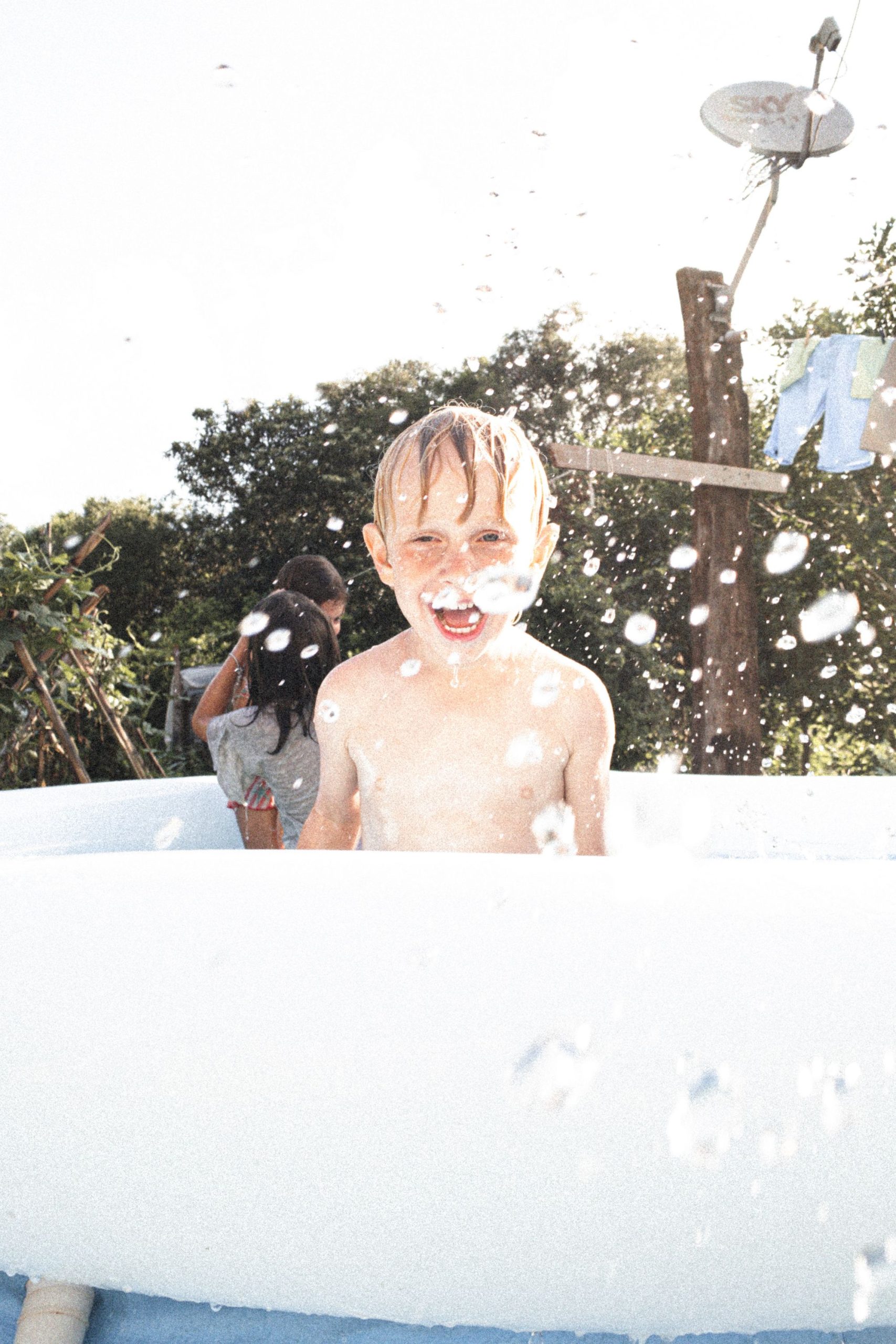 A boy laughing as water splashes around him