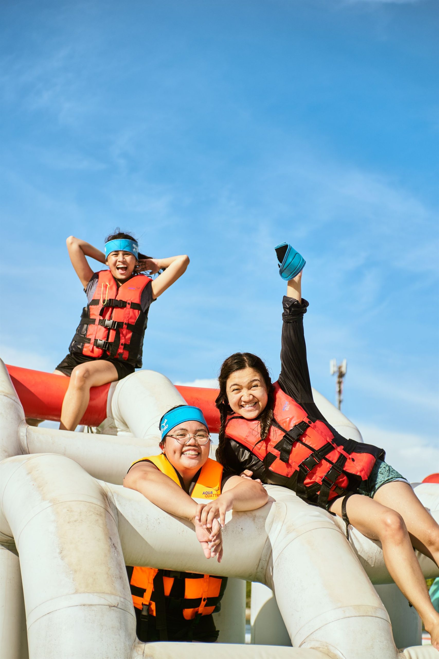 Friends in life jackets cheering on an inflatable under a blue sky