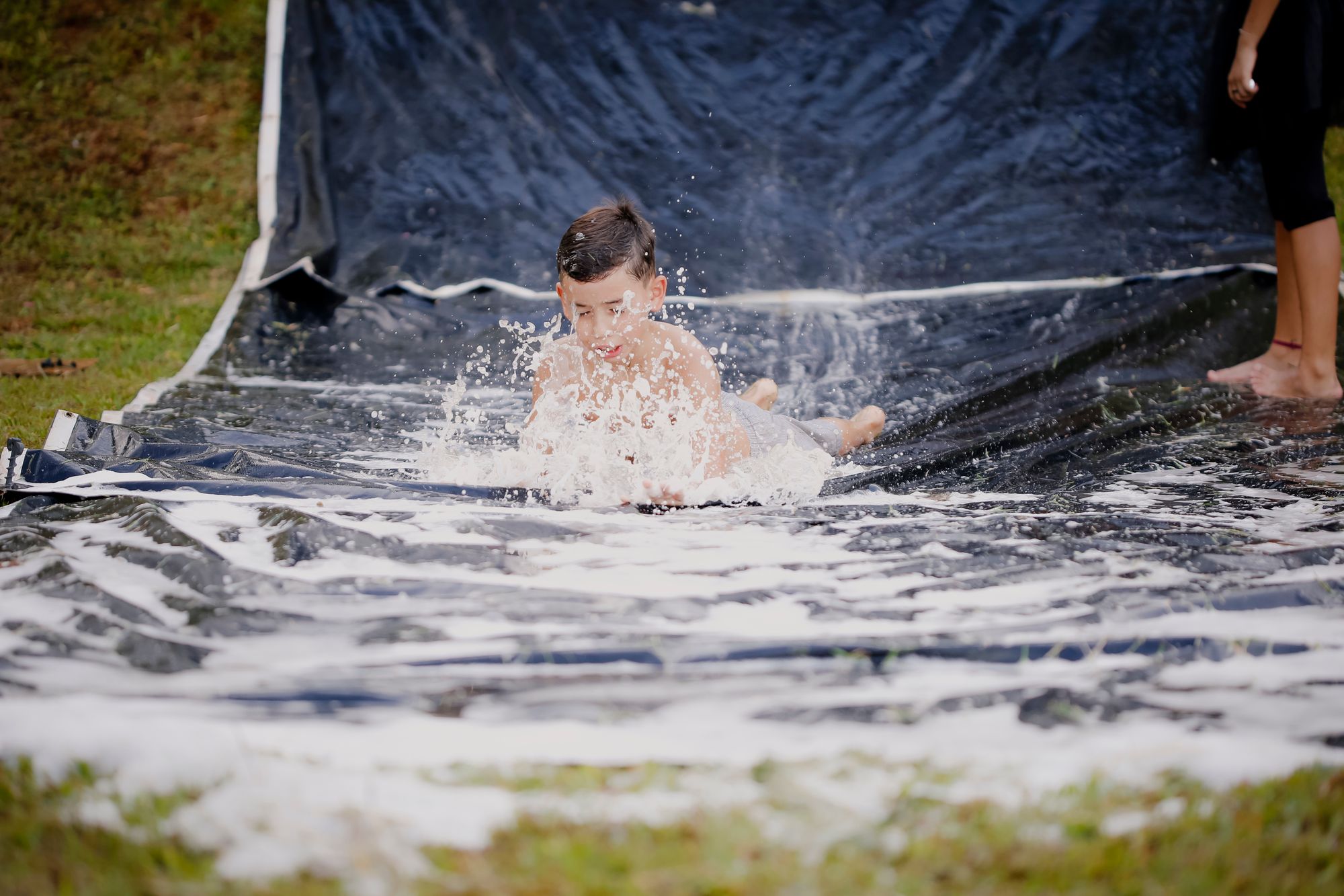 A child splashing down a backyard slip-and-slide