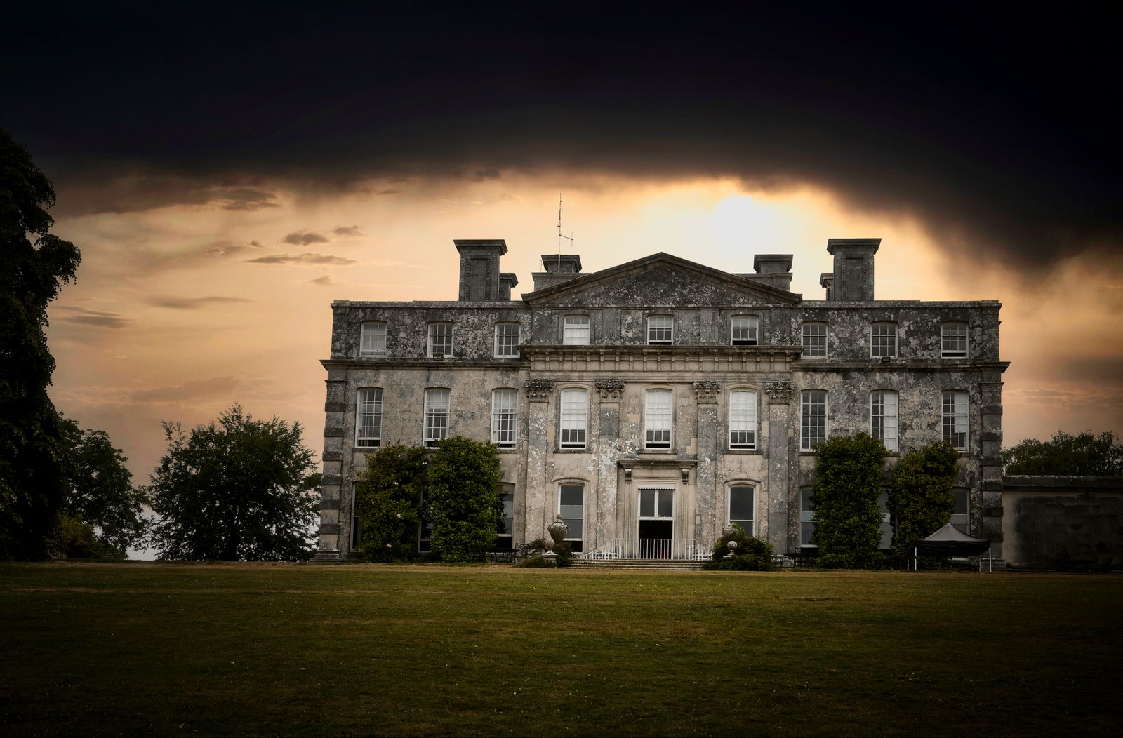 Manor with rooflines and trees lit