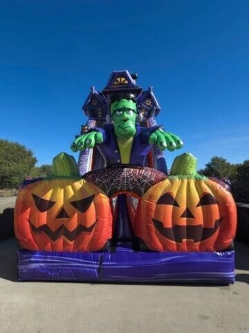 A haunted mansion inflatable with a monster on top and jack-o’-lanterns
