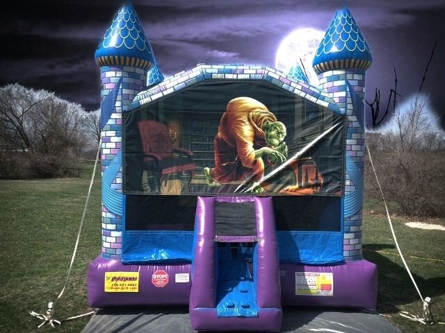 A Halloween bounce house with blue turrets and a haunted forest panel