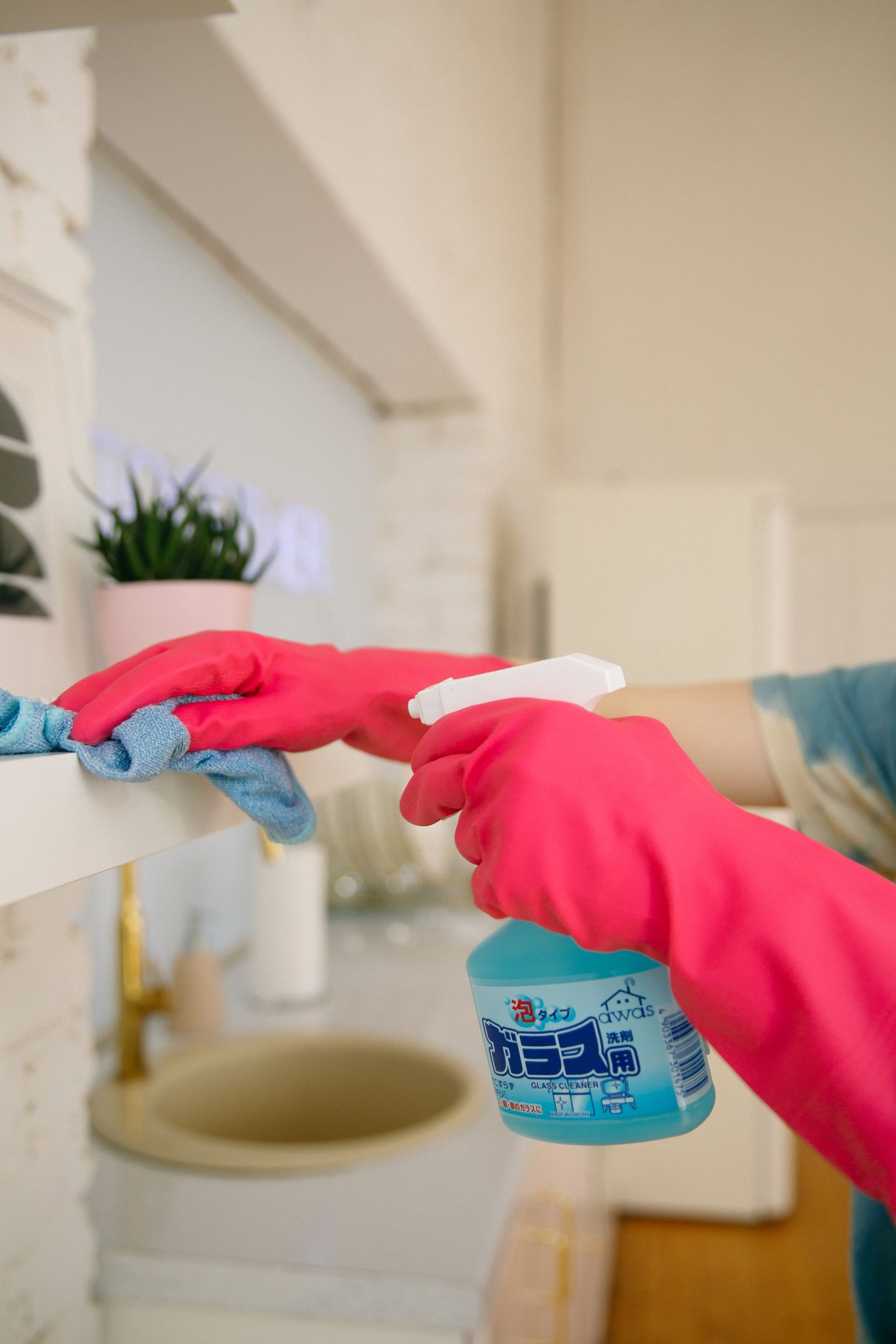 A gloved hand wiping down a surface with a cloth