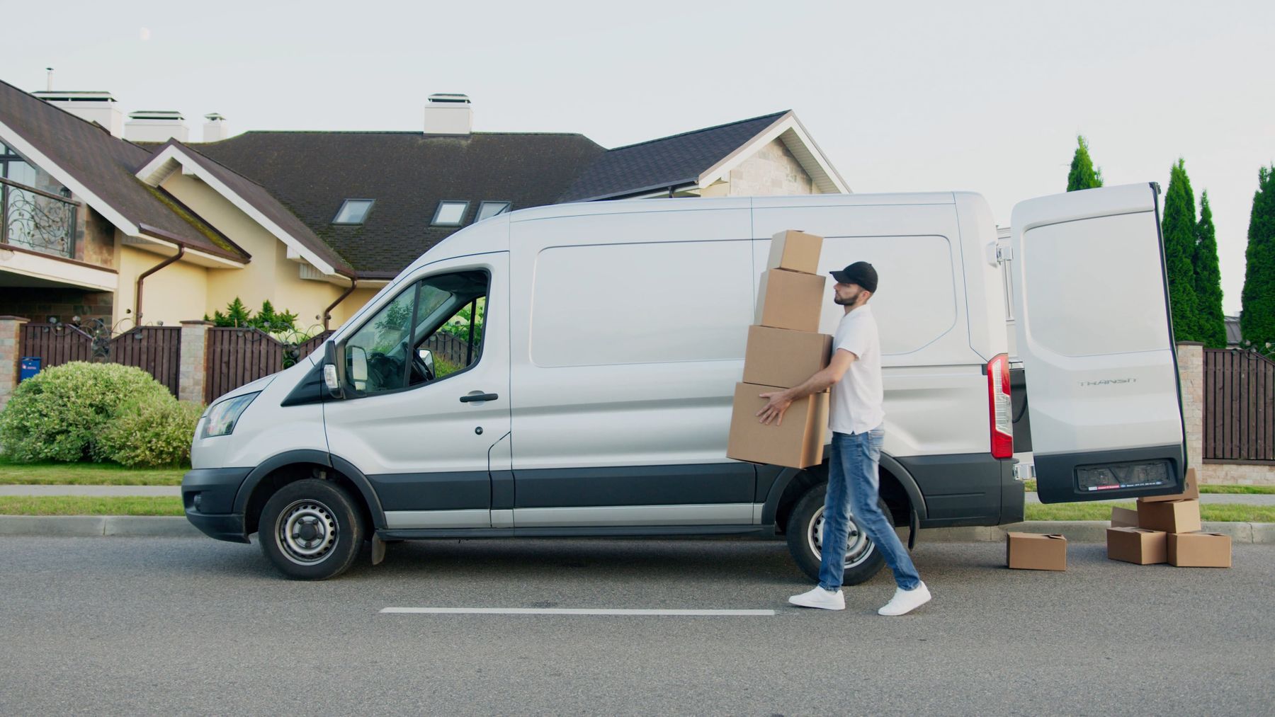 A delivery van parked in a driveway while a crew member unloads equipment
