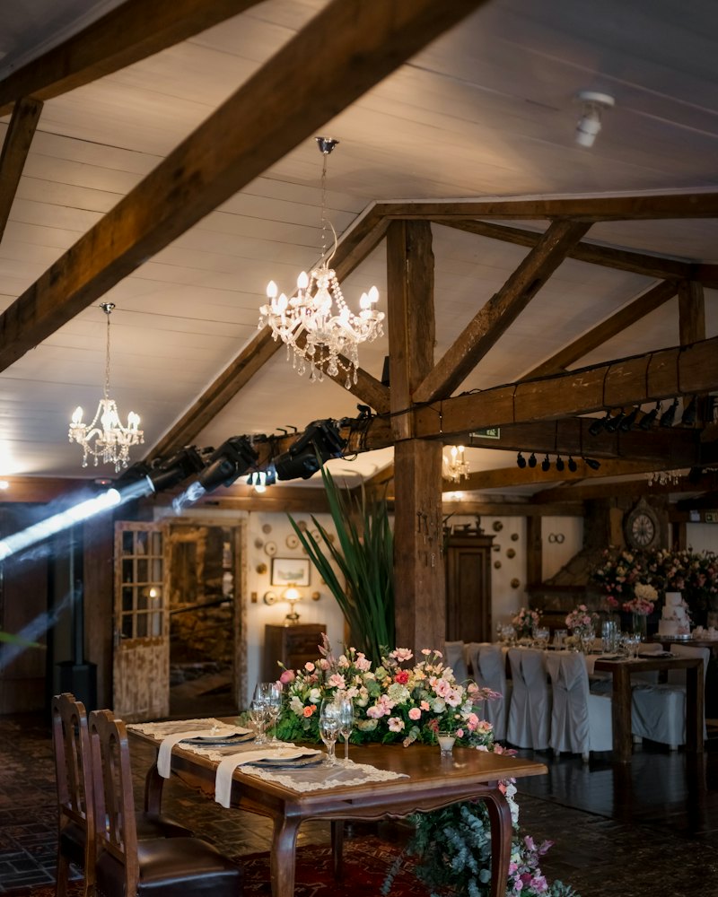 Rustic barn reception with chandeliers, wood beams and florals