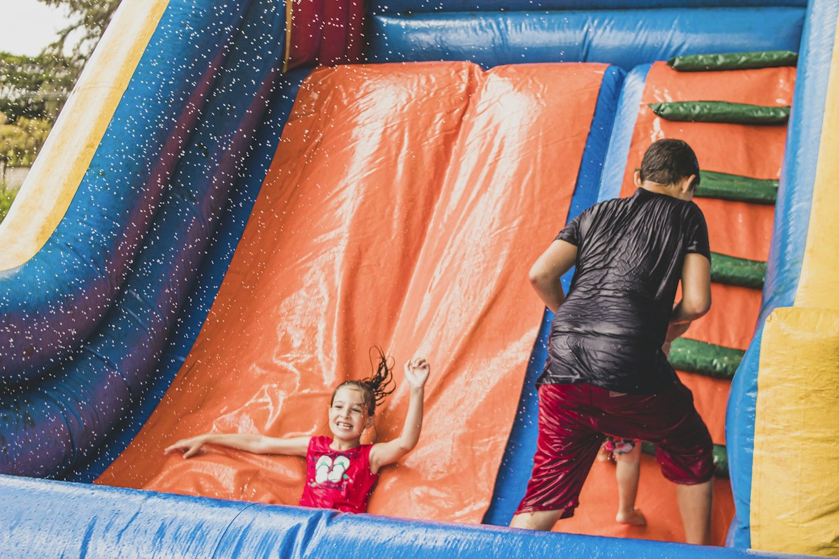 Kids racing down an orange inflatable slide