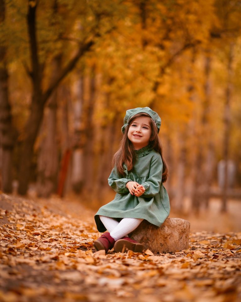 A girl sitting in an orange autumn forest