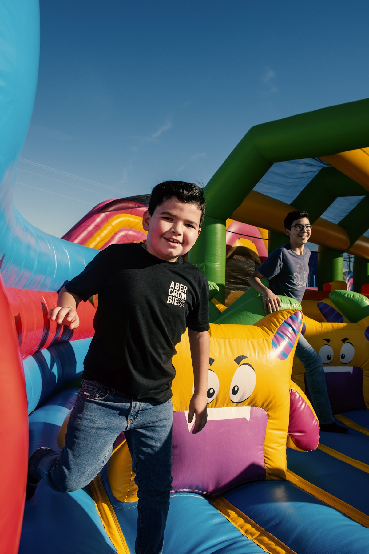 A smiling boy at a colorful bounce house in golden autumn light